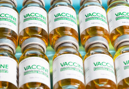 Vials of the coronavirus vaccine lie in a row on a blue background. Treatment concept and vaccine development, macroの写真素材
