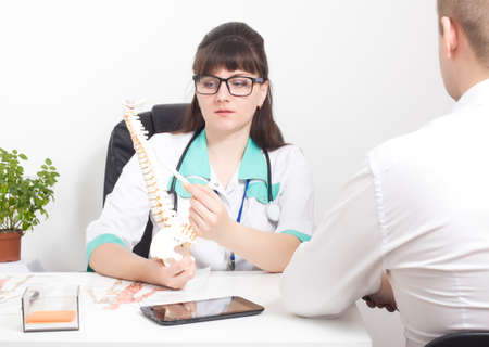 The doctor explains to the patient on the layout of the spine how the modern surgery on the wound will be performed laser puncture for protrusion and herniated discs, deformitiesの写真素材