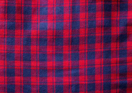 Red checkered material on clothes shirt, background. Macro