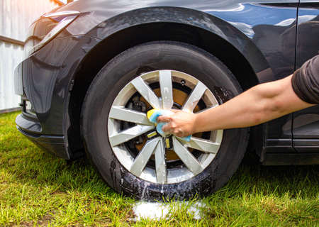 Hand washing car rims with a sponge with car shampoo for cleaning dirt and giving shineの写真素材