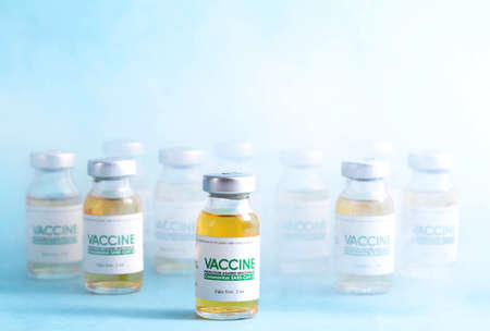 Coronavirus vaccine dose bottles on blue background covered in smoke. Kotsnept developing and...