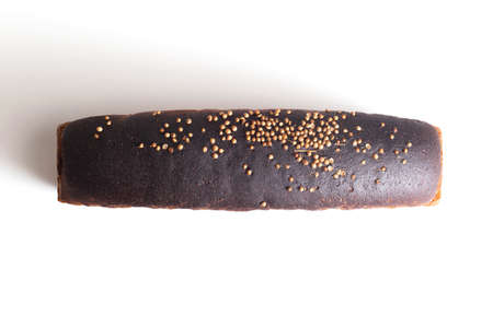 Loaf of black wheat bread with coriander seasoning on white plate, isolate