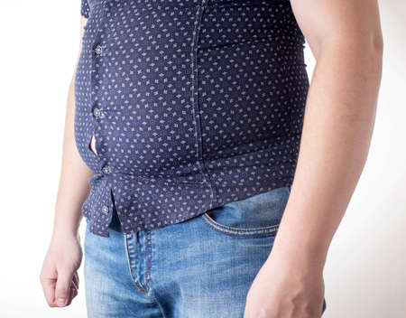 A man in a black tight shirt on a white background. Overweight, unhealthy diet and weight loss...