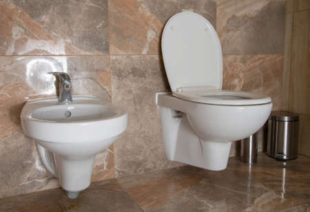 A toilet and a bidet for washing the genitals are combined in the bathroom. Toilet interior, brown ceramic tilesの写真素材