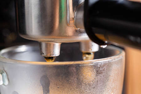 Hot coffee flows out of the espresso machine into a transparent mug, macroの写真素材
