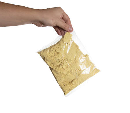 mustard powder in a sachet in a man's hand on a white background, isolate. close-up