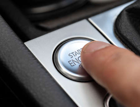 Man's finger presses modern car button to start car, macro. Technology