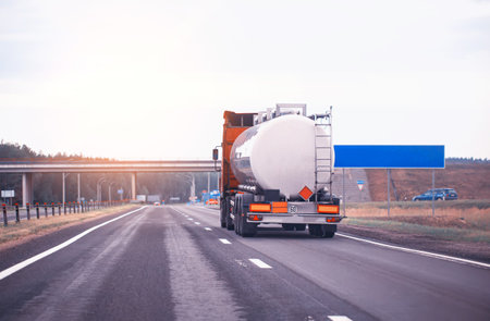 truck with semi-trailer tanker transports dangerous goods on the highway on the background of sunset, industry. Copy space for text, petroleumの写真素材