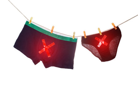 Men's and women's underpants hang on a clothesline with red crosses. Concept of male and female sexually transmitted infections, isolate. close-upの写真素材