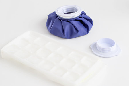 A medical blue cold bag with ice next to it. Pain relief and removal of edema with bruises