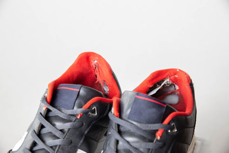 Torn backs in multicolored sports sneakers on a white background, isolate. Poor quality shoes. Copy space for textの写真素材