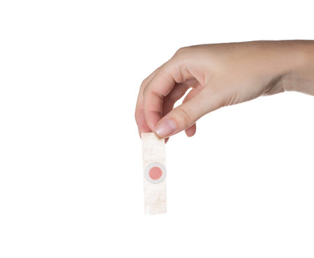 The girl holds in her hand a medical plaster against core calluses on the soles of the feet. White...