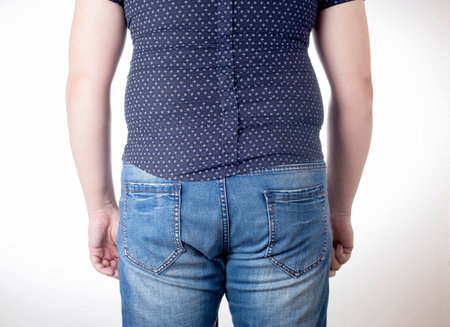 A man in a black tight shirt on a white background. Overweight, unhealthy diet and weight loss concept, close up.の写真素材