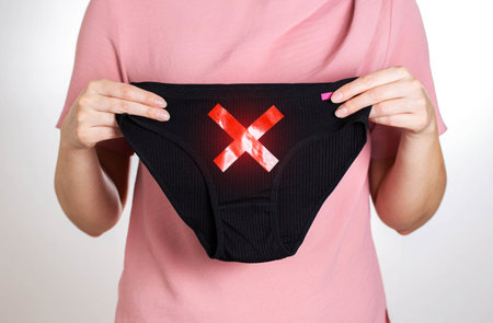 The girl is holding panties with a red cross. Concept of diseases of the female reproductive system,...