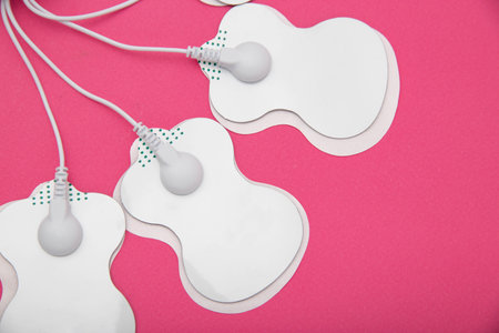 Electrical electrodes for stimulating the patient's body on a pink background.