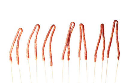 thin sausages for beer strung on wooden sticks on a white background, isolate, traditional