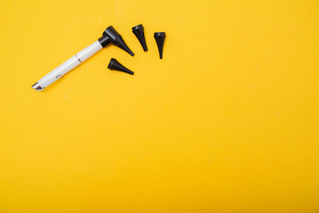 Medical device otoscope on a yellow background. Treatment of ear diseases and diagnostics in the otolaryngologの写真素材