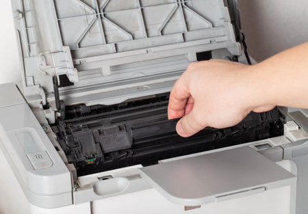 A man takes out a cartridge from a laser printer for maintenance and refilling toner