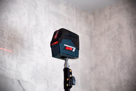 Construction laser level on the background of the wall, close-up. Smooth Coating Tool