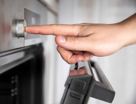 Modern oven with recessed function controls. Man's hand presses a recessed regulatorの写真素材