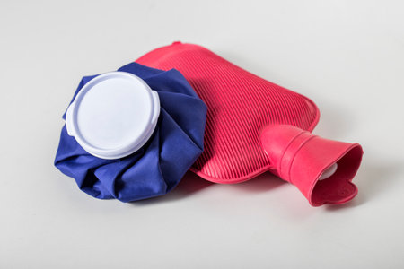 Red medical water heater and blue ice bag on a white background. The concept of treating diseases with heat and cold, heat therapy. Close-upの写真素材