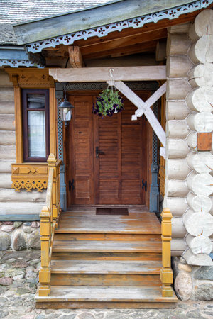 Wooden porch with steps and an entrance door to the village house. Ancient architecture, village traditionsの写真素材