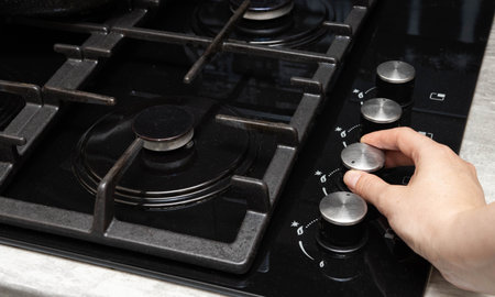 A woman turns on a gas stove with piezo ignition. Turns the gas regulator, danger