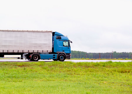 A truck with a semi-trailer transports cargo in rainy weather on a slippery road. Automobile cargo transportation.の写真素材