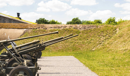 Military guns installed on the street against the backdrop of a bomb shelter. Military conflict, aggression.の写真素材