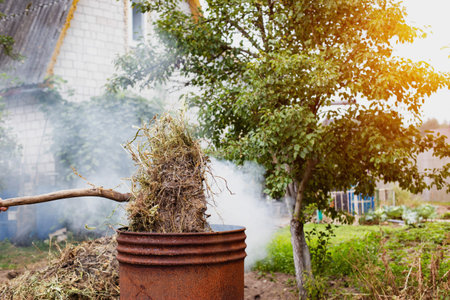 Burning dry grass and garbage in the country in the fall in an iron barrel. Penalty and fire hazard if weed is burned incorrectly. Copy space for textの写真素材