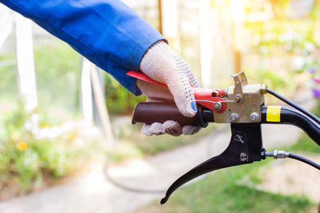 A man presses the handle of the safe shutdown of a walk-behind tractor with his hand during work.の写真素材