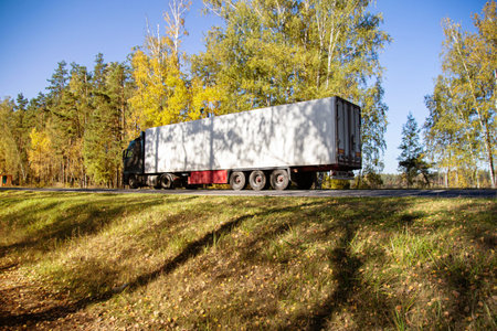 A truck with a refrigerated semi-trailer transports perishable goods against the backdrop of a...