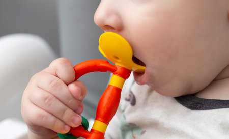 A child holds a rubber toy massager for teething in his hand. Itching and salivation from the mouth....