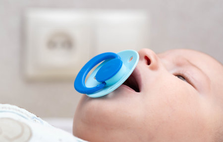 Blue latex pacifier in baby's mouth. The concept of orthodontic comfortable nipple without changing...