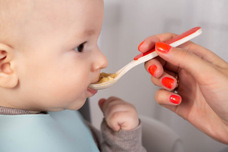The first feeding with fruit puree for a baby boy who is 6 months old.の写真素材