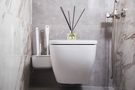 Aroma diffuser air freshener stands on a hanging toilet bowl in the toilet. The concept of a pleasant aroma in the toilet, close-upの写真素材