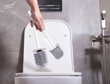 The girl in her hand holds three silicone brushes for the toilet. The concept of care and hygiene for the toilet bowl and seat. Prevention of pollution and cleaning of bacteria.の写真素材
