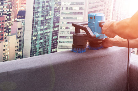 Cleaning the back of a black sofa with a special electric brush. Sofa cleaning service.の写真素材
