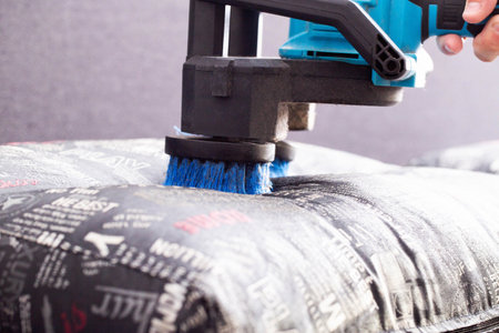 Cleaning the sofa with special equipment, an electric brush to lift the pile on the upholstery of the sofa. Dry cleaning of upholstered furniture.の写真素材