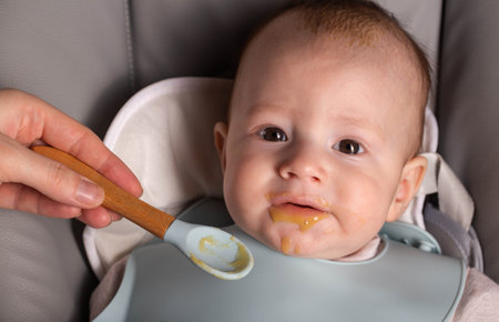 A 6-month-old baby tries porridge for the first time. Feeding babies. Vitamins in food, calories.の写真素材