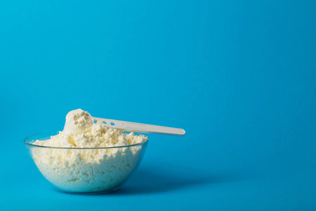 Plate with dry milk mixture enriched with vitamins, minerals and bifidobacteria on a blue background. Copy space for text, oligosaccharidesの写真素材