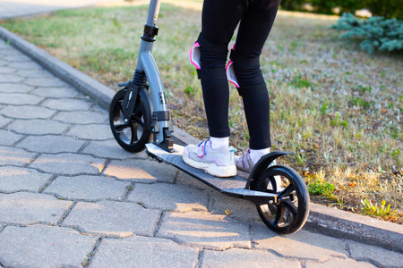 A beautiful girl in a pink protective outfit rides a scooter through the streets of the city in...