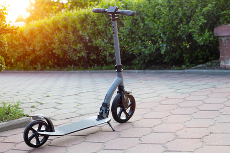 Scooter in the city on the alley and green bushes. The concept of the cost of renting scooters