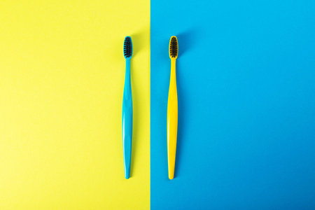 Yellow and blue toothbrush with charcoal coating on a yellow-blue background. The concept of dental and oral hygiene in dentistry. Copy space for textの写真素材