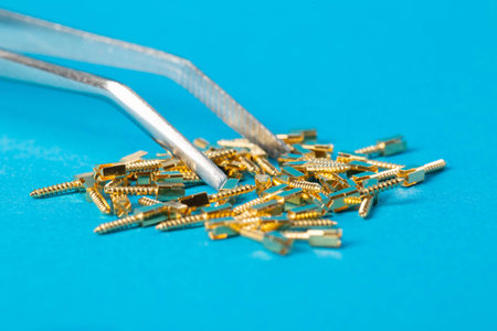 Metal dental pins on a blue background in tweezers in dentistry. Installation of pins for a dental crown in orthodontics.の写真素材