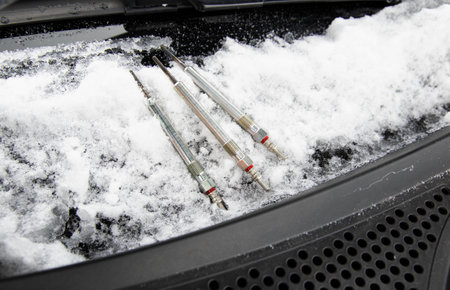 Rod ceramic glow plugs on an icy car hood in winter. Heating elements of the combustion chamber of a...