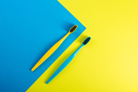 Yellow and blue toothbrush with charcoal coating on a yellow-blue background. The concept of dental and oral hygiene in dentistry. Copy space for text. Prevention of cariesの写真素材