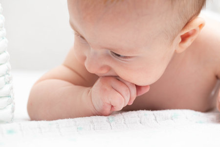 A little boy aged three years old sucks his fists in his mouth. The concept of the sucking reflex in children.の写真素材