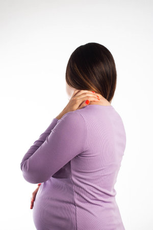 Neck pain in a pregnant girl in a purple blouse on a white background. The concept of muscle spasm due to a herniated disc in the cervical spine, neurologicalの写真素材