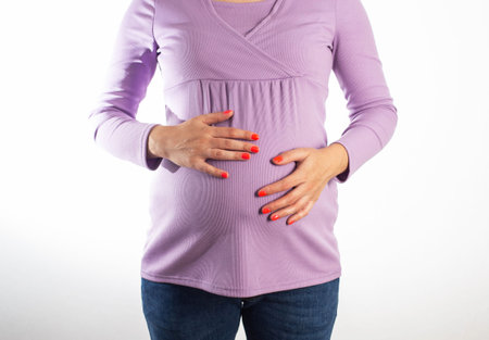 A pregnant girl with a purple sweater holds her swollen belly. Concept of digestive problems in...